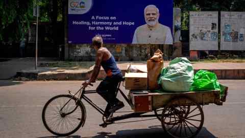 A man rides a cycle rickshaw past a billboard featuring Indian Prime Minister Narendra Modi ahead of this week’s summit of the G20 nations in New Delhi