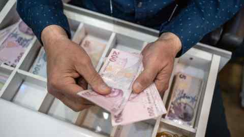 A vendor counts Turkish Lira banknotes inside a shop in Ankara